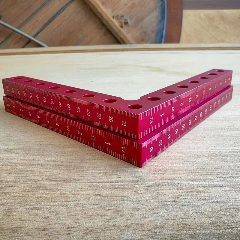 Red L-shaped ruler with measurement markings for use with angle clamp in woodworking