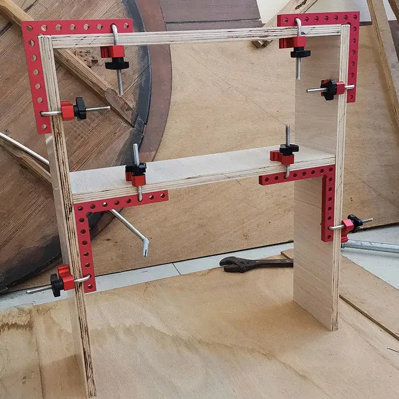 Wooden frame secured with red metal brackets and black clamps using a 90 degree angle clamp