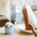 Portable Balashov Mini Ultrasonic Air Humidifier emitting vapor beside an open book