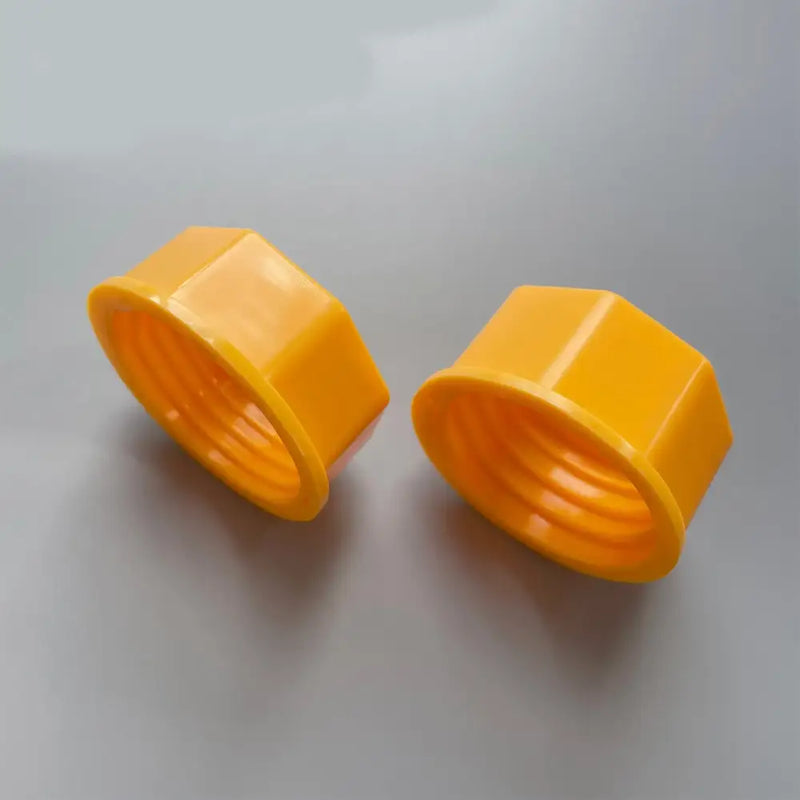 Two yellow threaded hexagonal nut caps for tool maintenance and repair use