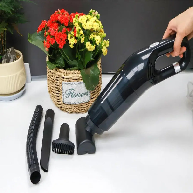 Handheld USB charging portable vacuum cleaner with attachments beside a potted flowering plant