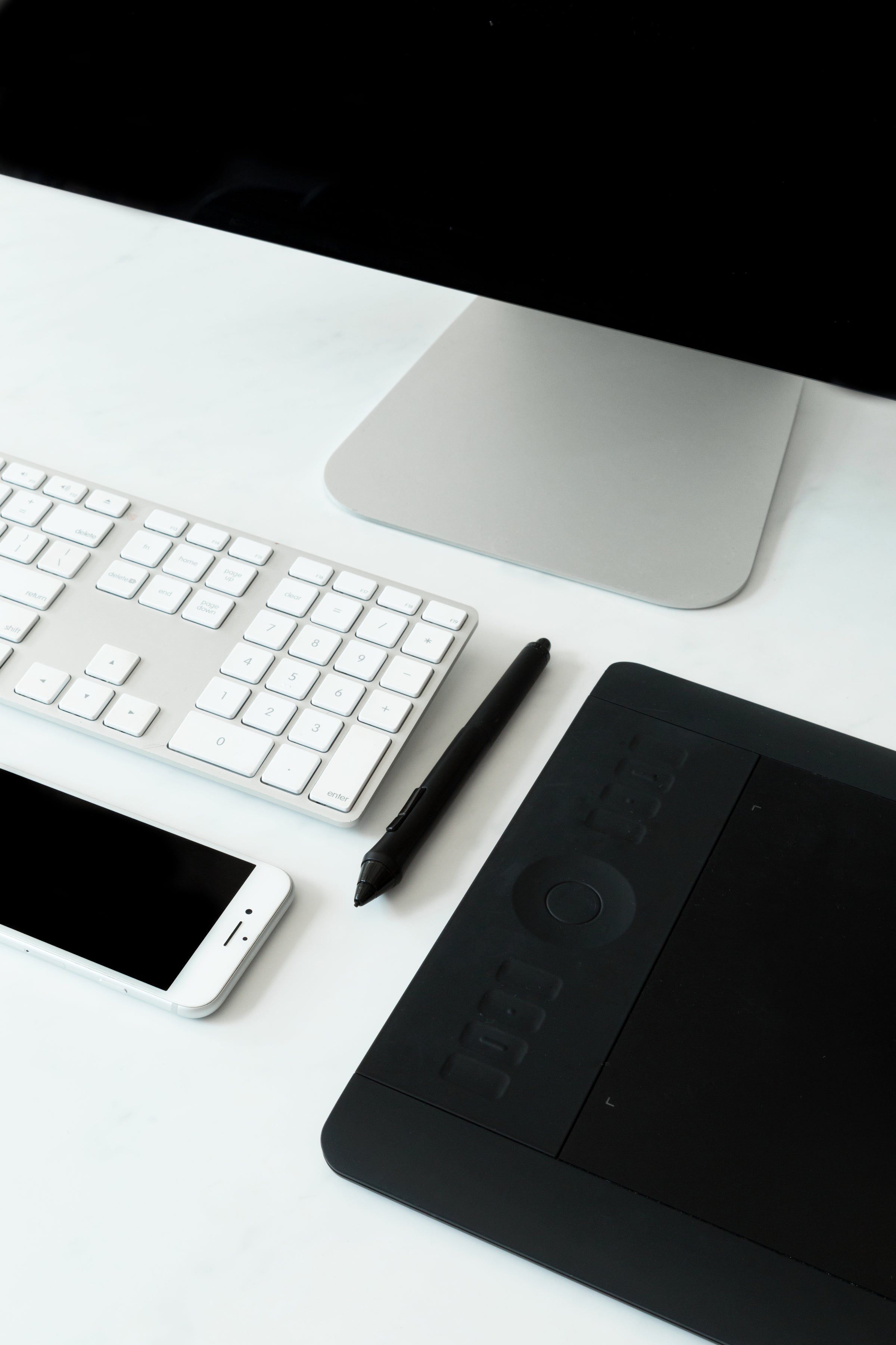 Modern workspace desk setup with computer, keyboard, phone, and drawing tablet