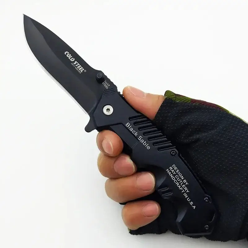 Black folding tactical knife in gloved hand promoting IROVNE DIY Supplies for precision tasks