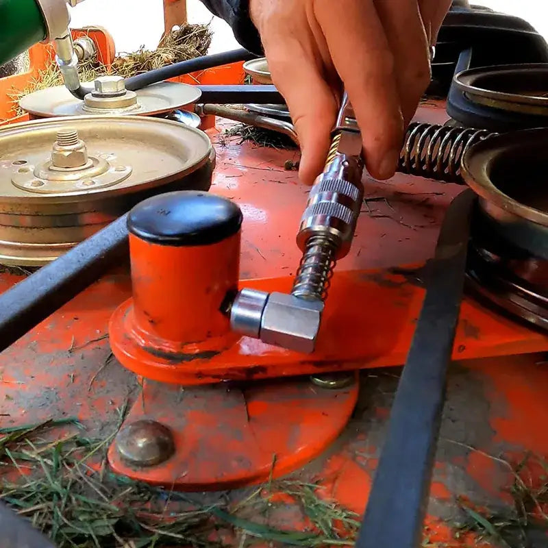 Orange hydraulic jack on a dirty surface with mechanical parts near NoEnName Null Grease Coupler