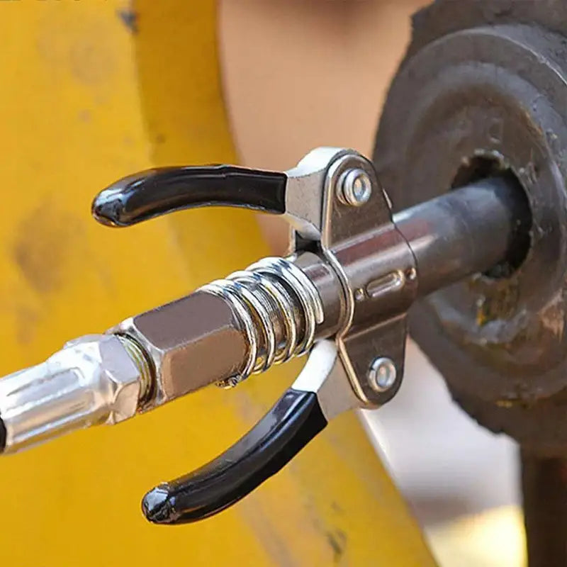 Fuel nozzle with metal spring on a yellow surface for NoEnName_Null Grease Gun Coupler