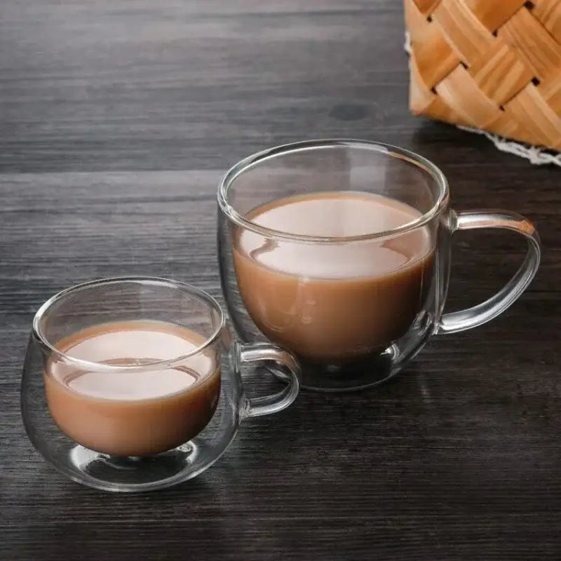 Two transparent double wall glass cups filled with creamy coffee or hot chocolate