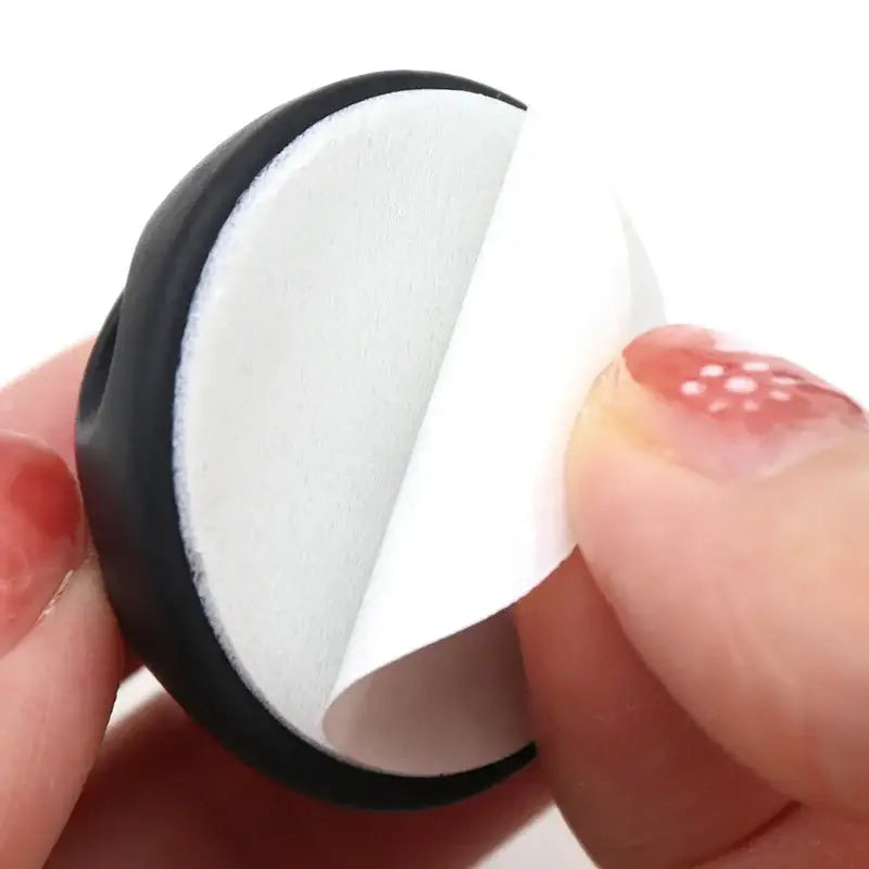 Crescent-shaped black and white silicone USB cable manager held between fingers for organization