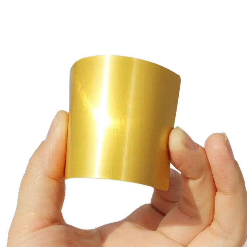 Curved shiny gold metal sheet held between fingers, showcasing NoEnName_Null Type Hand Tool Parts