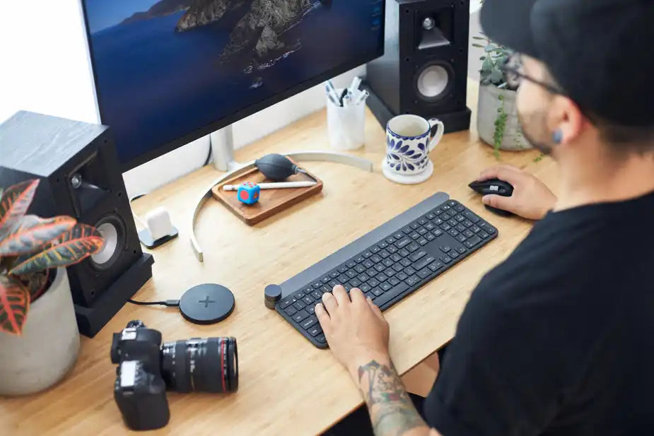 Photographer editing photos on desktop computer at modern tech workspace with camera and gadgets